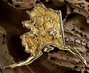 A gold nugget in the shape of Alaska with diamond