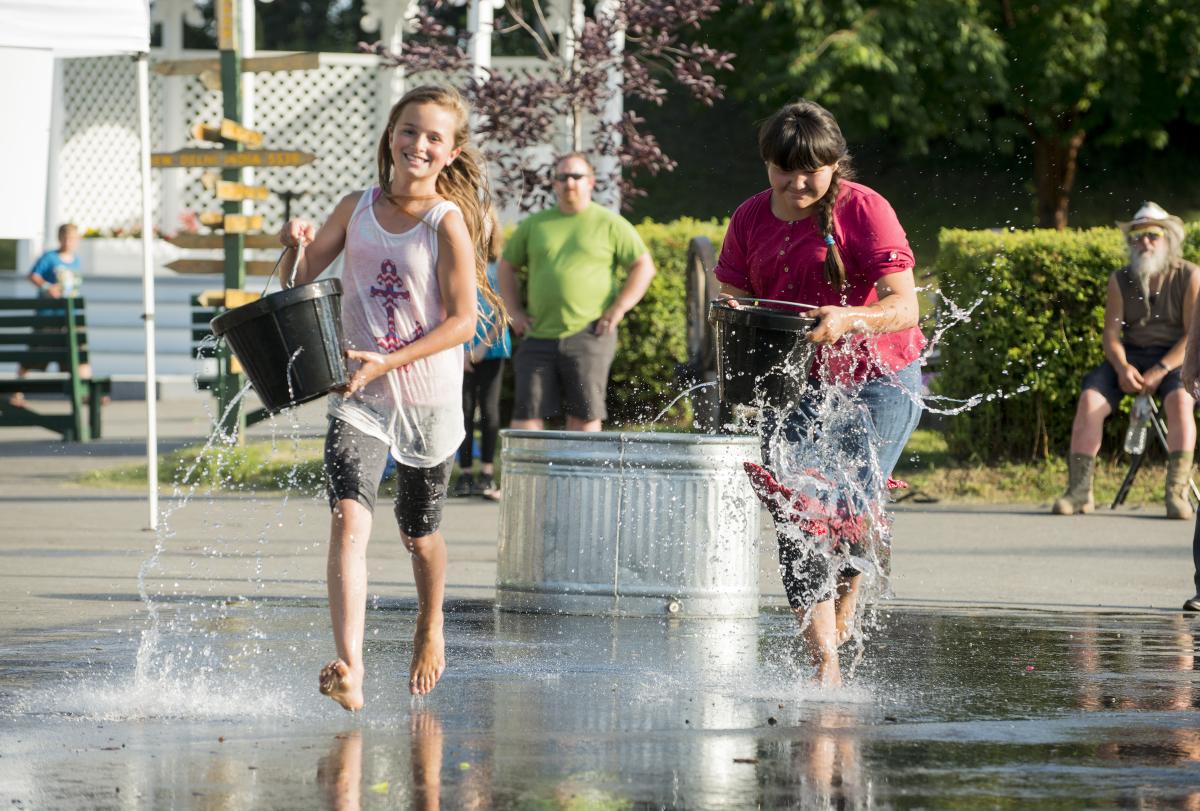 Children running with buckets full of water in an "Old Tyme Games" competition at the Golden Days Celebration.