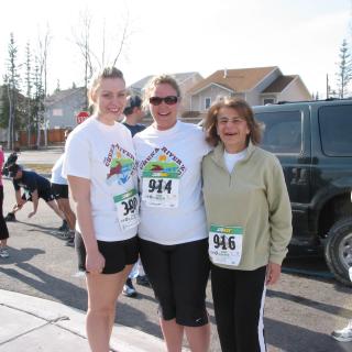 Three people standing and smiling, about to race in the Chena River Run