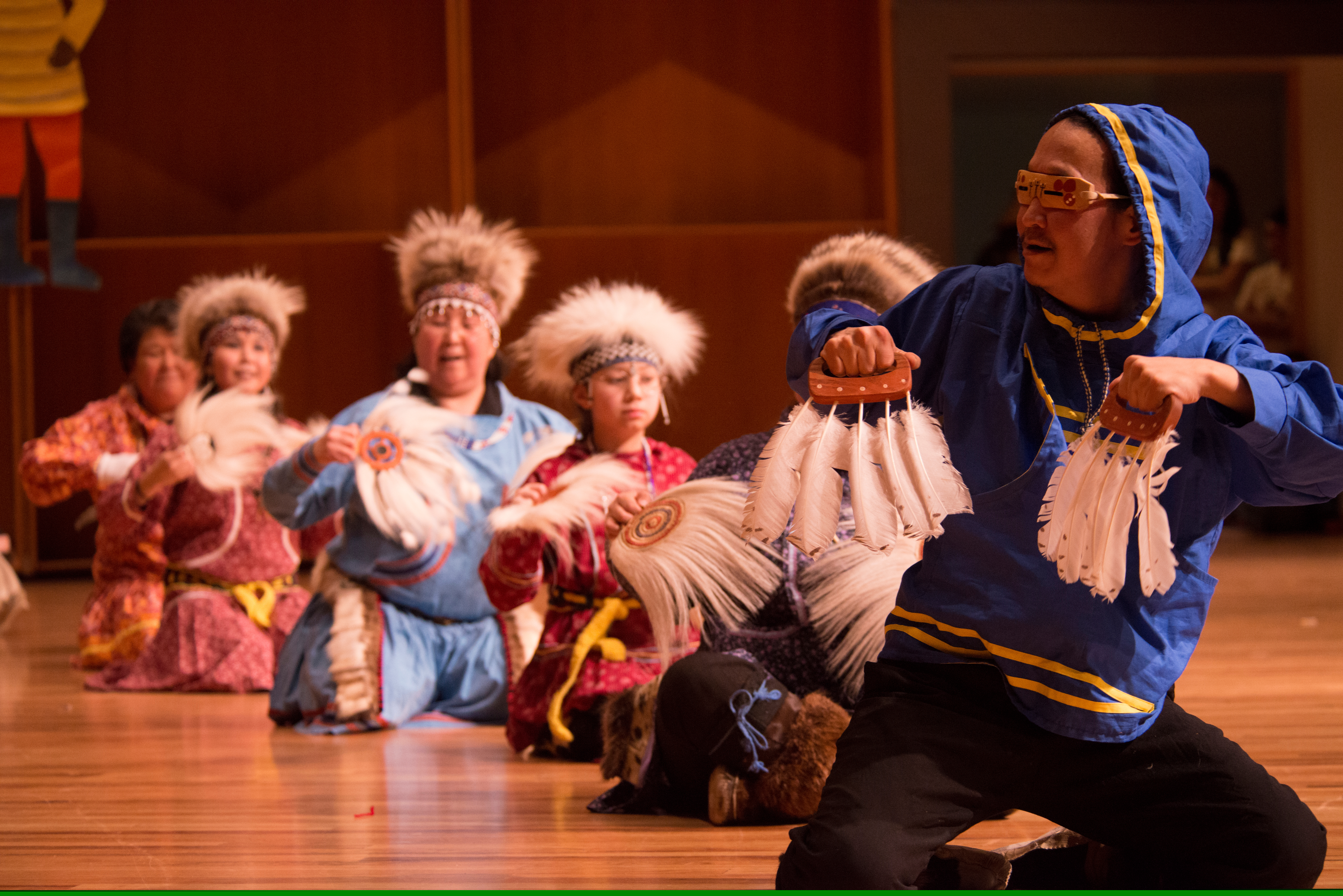 Alaska Native man and women dancing in traditional costumes