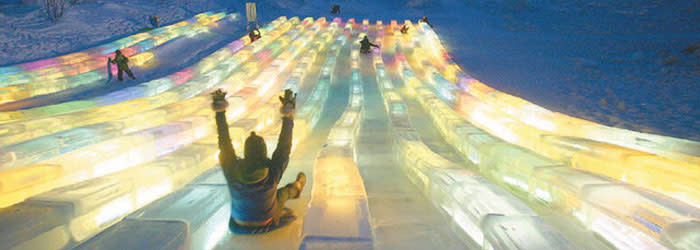 Person going down glowing ice slide at World Ice Art Championship in Fairbanks, AK