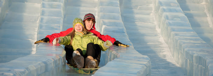Two people riding a sled on an ice slide