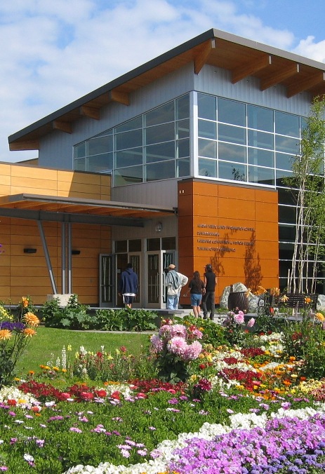 The Morris Thompson Cultural and Visitors Center, surrounded by flowers and blue sky