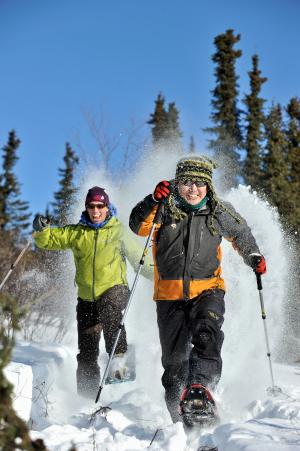 Smiling friends snowshoeing through the boreal forest in Interior Alaska.